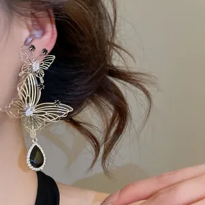 Detail shot of French hollow butterfly earrings featuring a sparkling black teardrop pendant