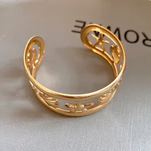Macro view of a golden hollow cuff bracelet featuring starfish and seashell motifs