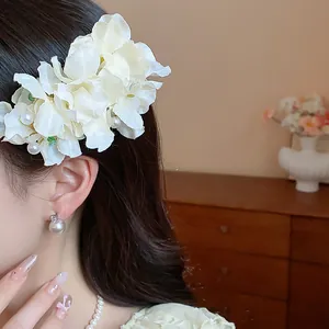 Close-up detail of a delicate white fabric flower hair clip with elegant pearl accents