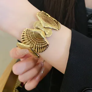 Close-up of gold seashell hollow open bangle worn on wrist for holiday style