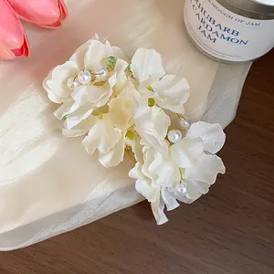 Detailed close-up of ethereal white fabric flower hair clip with elegant pearl accents.