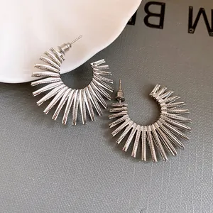 Detailed shot of silver sunburst C-shaped hoop earrings with a textured spike design