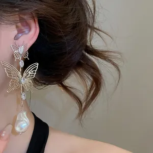 Detail view of hollow butterfly earrings with marquise crystals and baroque pearl drop.