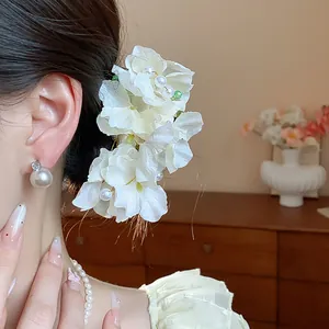 Close-up of elegant white fabric flower hair clip with pearls worn by an Asian model