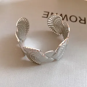 Detail view of a silver-finish open cuff bracelet featuring intricate seashell textures.