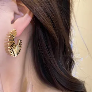 Close-up of golden geometric C-shaped earrings with a unique pleated and textured design
