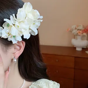Close-up of elegant white fabric flower hair clip with pearl accents on woman's hair