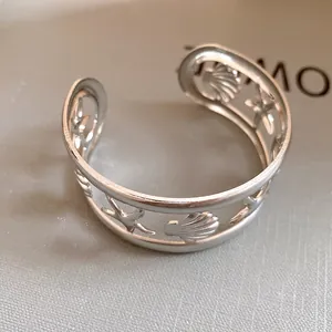 Detailed macro view of hollow starfish and seashell patterns on silver cuff bracelet