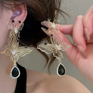 Detail view of French style hollow butterfly earrings with black teardrop crystal pendant