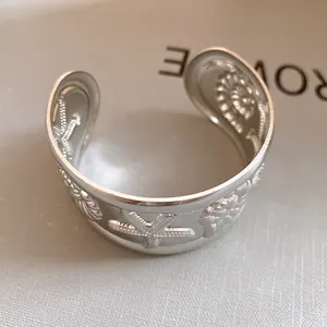 Detailed macro view of silver open cuff bracelet featuring starfish and seashell motifs