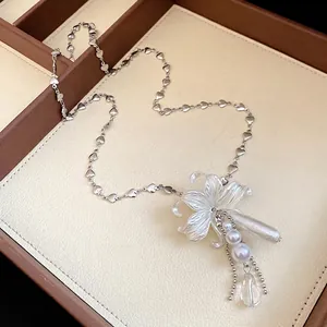 Élégant collier argenté orné d'un pendentif fleur blanche, de perles et d'une goutte cristal.
