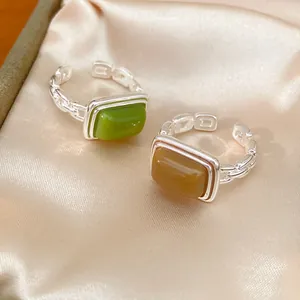 Close-up of minimalist resin square open rings in green and brown finishes