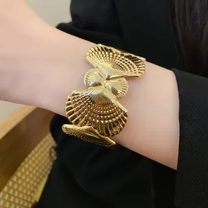 Close-up view of a gold-tone scallop shell textured open cuff bracelet for beach vacation.