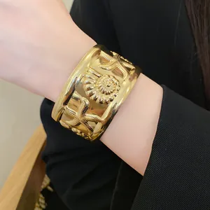 Detailed view of a golden wide cuff bracelet featuring starfish and shell relief on wrist