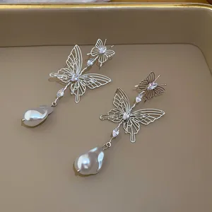 Close-up of French-style hollow butterfly earrings with teardrop pearl drops.