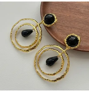 Close-up detail of vintage gold textured double hoop earrings featuring black spherical studs