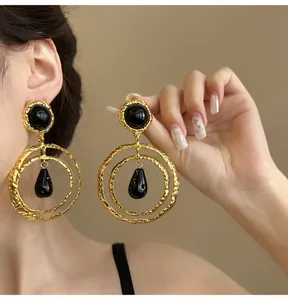 Close-up detail of vintage ethnic gold hoop earrings with black teardrop pendants.