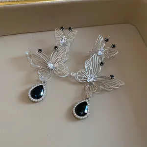 Detailed shot of silver hollow butterfly earrings featuring elegant black water drop stones.