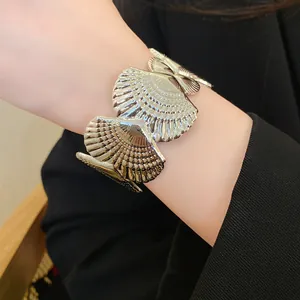 Close-up view of a silver metallic seashell cuff bracelet featuring detailed scallop textures.