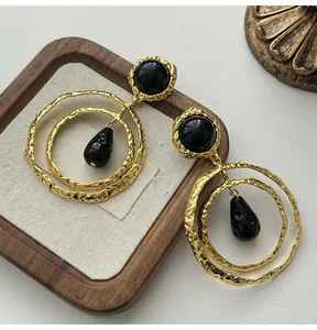 Retro statement hoop earrings with black teardrop pendant and textured gold finish.