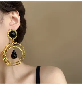 Detailed macro shot of vintage gold hoops with black resin accents worn by a model