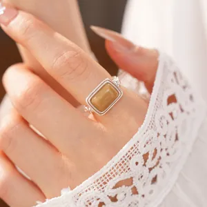 Close-up of stylish square resin ring in silver frame worn with lace sleeve