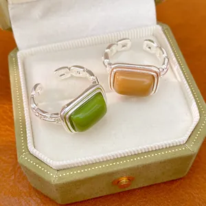 Close-up detail of green and amber resin square open rings inside a vintage jewelry box