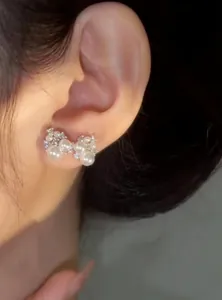 Close-up view of an elegant silver needle bow-knot pearl and zircon stud earring.