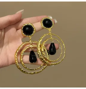 Detailed view of vintage hammered gold circular earrings with black resin pendants