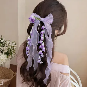 Dettaglio di fermaglio per capelli a fiocco in chiffon viola con mughetti pendenti