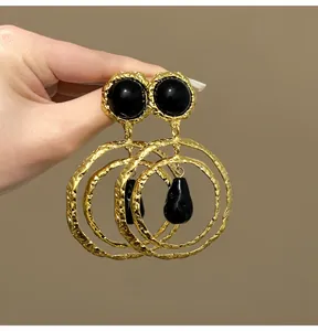 Detailed view of vintage gold textured hoop earrings with black teardrop pendants