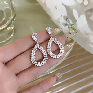 Close-up of elegant hollow teardrop zircon earrings with silver needles for women