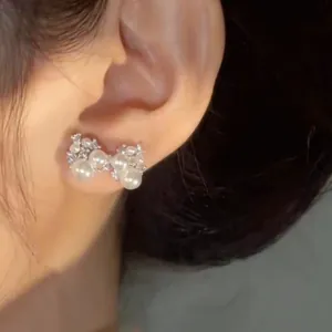 Detailed view of a silver needle bow-knot earring adorned with shiny pearls and zircons