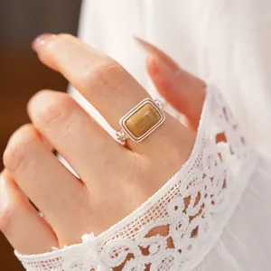 Detail shot of a minimalist silver open ring with a rectangular yellow resin stone on hand