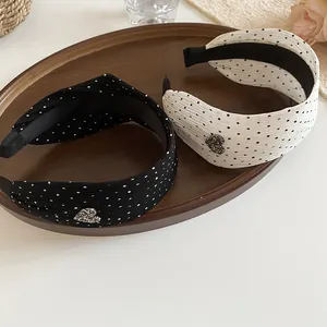 Close-up of wide polka dot headbands with heart charms in black and white finish