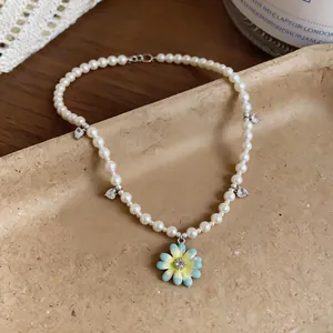 Close-up detail of a pearl necklace featuring an enamel flower and heart zircon charms