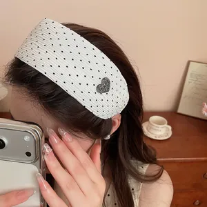 Macro detail view of white polka dot wide headband featuring a sparkling rhinestone heart