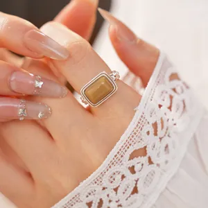 Close-up of minimalist rectangular resin ring on finger with white lace background