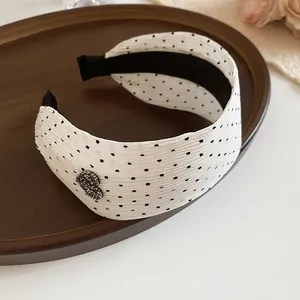 Close-up of white polka dot headband with sparkling heart accent on wooden tray.