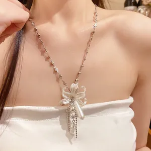 Vue détaillée d'un collier pendentif fleur perle blanche porté par un mannequin.