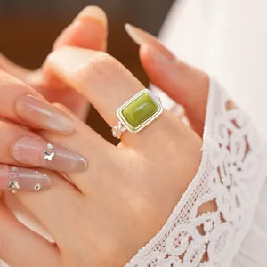 Close-up view of an elegant square green resin ring worn on hand with white lace sleeve