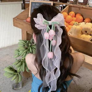 Primo piano del fermaglio per capelli con fiocco in chiffon rosa e ciondoli a tulipano