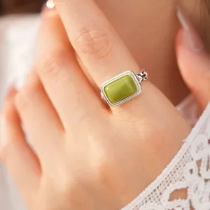 Macro view of a minimalist silver adjustable ring with a green square resin stone