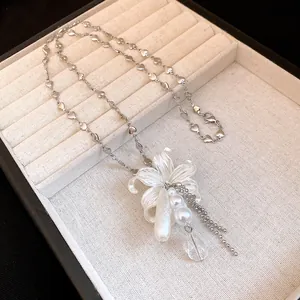 Gros plan détaillé du pendentif fleur en perles et de la chaîne à maillons cœur en argent