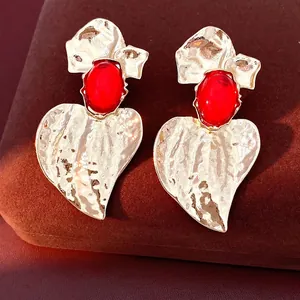 Statement gold leaf earrings with red oval resin stone and silver needle posts.