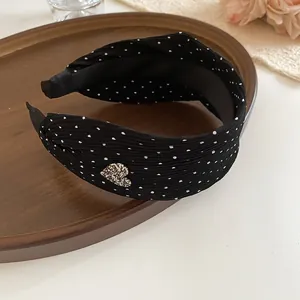 Close-up of black polka dot headband with sparkling heart detail on wooden tray