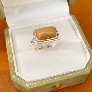 Detail view of a caramel resin rectangular ring in an elegant green velvet jewelry box