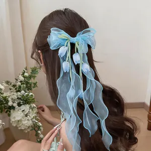 Dettaglio di un fermaglio per capelli con fiocco in chiffon blu e fiori di tulipani