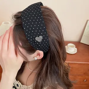 Close-up of a stylish black polka dot headband featuring a sparkly heart charm on a model.