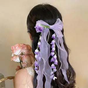 Dettaglio del fermaglio per capelli a fiocco in chiffon viola con fiori pendenti